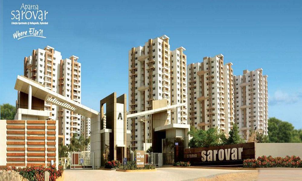 Entrance view of Aparna Sarovar residential apartments in Hyderabad featuring modern high-rise buildings, gated community, and landscaped surroundings.