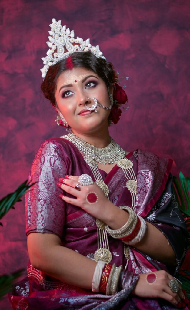 Indian bride in traditional attire with jewelry and makeup, posing elegantly.